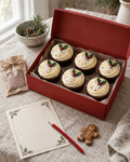 Christmas Eve Box, a red gift box with six white swirled Christmas cupcakes, a sachet of hot chocolate, a gingerbread man and a letter to Santa with a red pencil