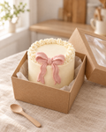 Small ivory bento cake with a ruffled edge and a piped dusty rose bow