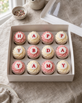 Message Cupcakes: twelve cupcakes in white cases with pink and white buttercream swirls, each topped with a flat white sugar disc