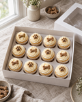 Pupcakes: twelve small dog-safe cupcakes in white paper cases with swirls of pale yoghurt frosting, each topped with a little bone-shaped biscuit or a piped paw print