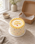 New Home Bento: a 4 inch bento cake in smooth cream buttercream with a yellow ruffled border, colourful sprinkle dots round the side and one small red piped heart under the message
