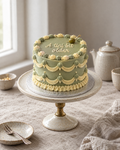 A Tini Bit Older Lambeth Cake: smooth olive green buttercream with pale yellow and green shells and swags, and one green cocktail olive on a little cocktail stick on the top