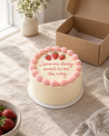 On the Way Bento: a 4 inch bento cake in smooth cream buttercream with a pink shell border and three small piped strawberries on the top