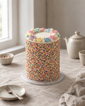 Sprinkle Party Cake: a tall round cake with the sides completely covered in rainbow sprinkles, a white buttercream top with a ring of pastel rosettes and a few white chocolate balls
