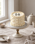Couple Doodle Cake: smooth cream buttercream with cream shell borders and colourful sprinkle dots round the edge