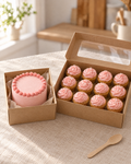 A pink bento cake beside a box of 12 matching pink cupcakes