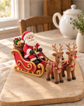 Santa, Sleigh and Reindeer Cake Topper Set laid out on a wooden board