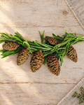 10 Christmas Pine Cone Cake Toppers laid flat on a wooden board