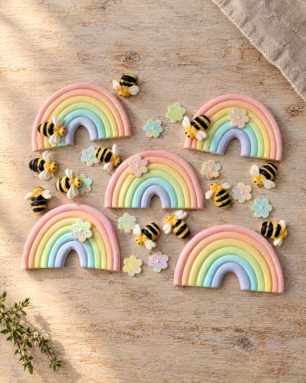 Rainbow, Bee and Flower Cake Toppers laid flat on a wooden board