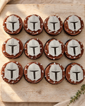 12 Mandalorian Cupcake Toppers laid flat on a wooden board