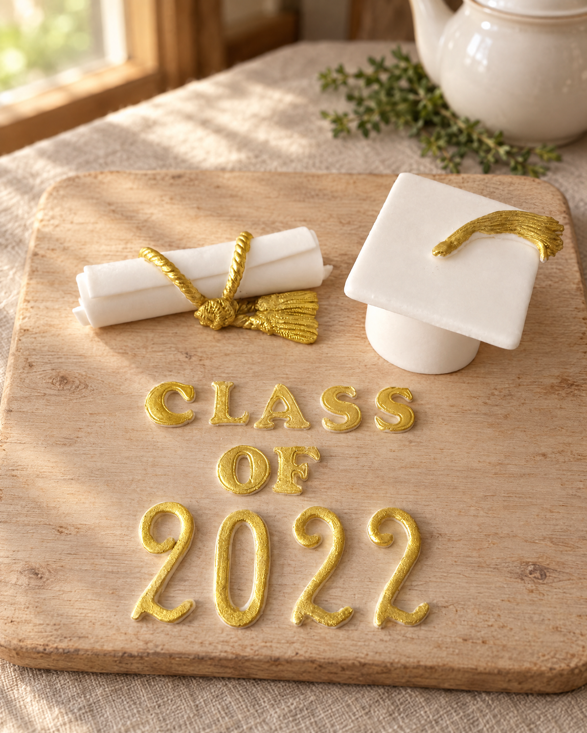 Graduation Cap and Scroll Cake Topper Set laid out on a wooden board