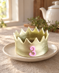 Gold Gum Paste Crown Cake Topper on a cream plate