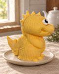 Knitted Dinosaur Cake Topper on a linen tablecloth